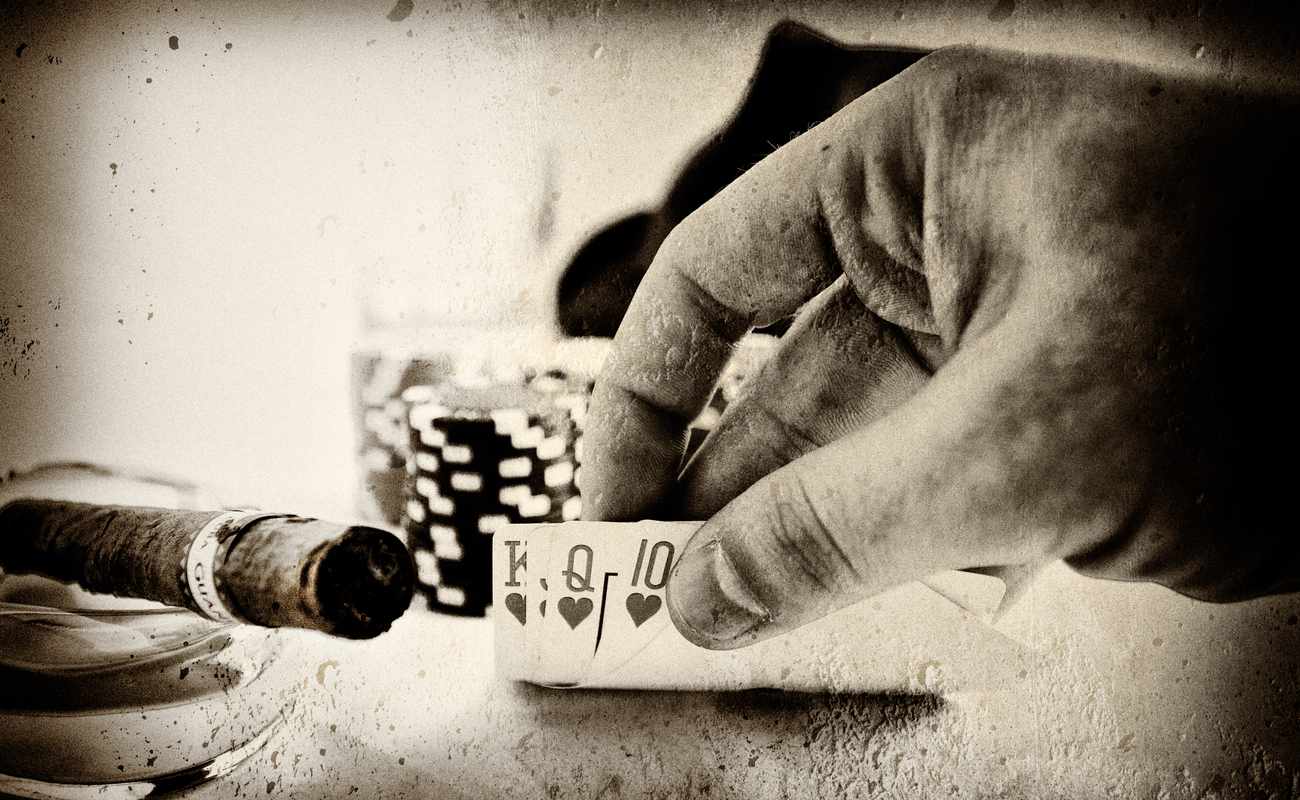 Old black and white picture of someone playing poker and a cigar next to them