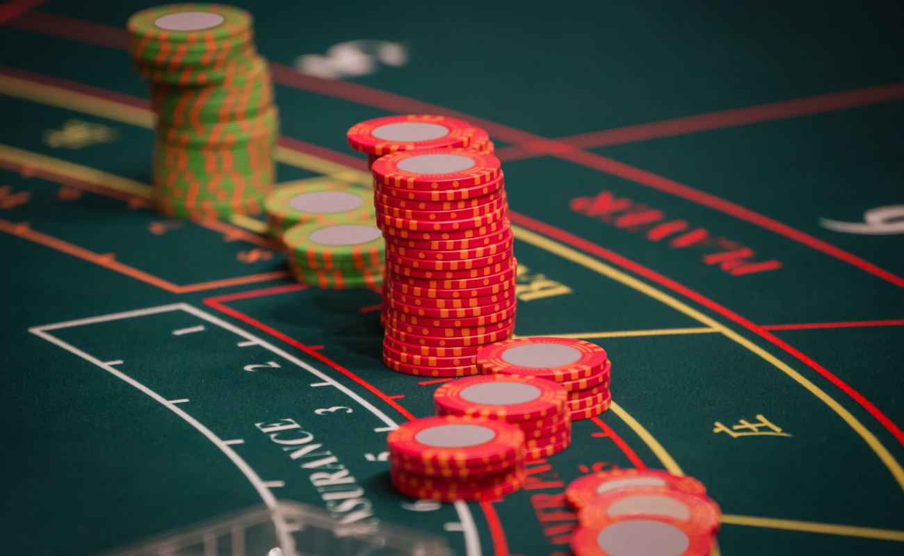A Hand of Dealer Organizing the Red and Green Baccarat Chips on Baccarat Gaming table