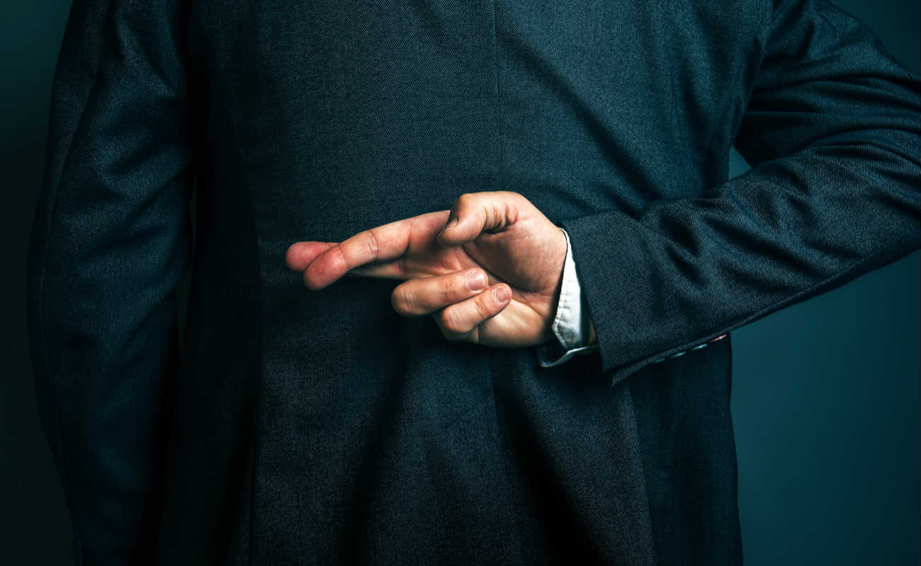 male entrepreneur holding fingers crossed behind his back