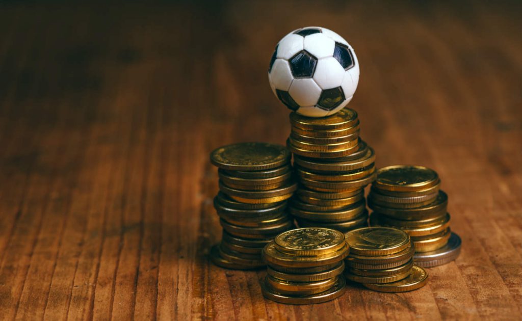 Stacks of coins with a football ball on the top of one of them.