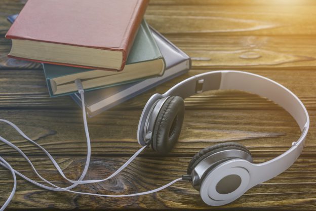 The concept is to listen to audiobooks. white headphones are connected to the book.